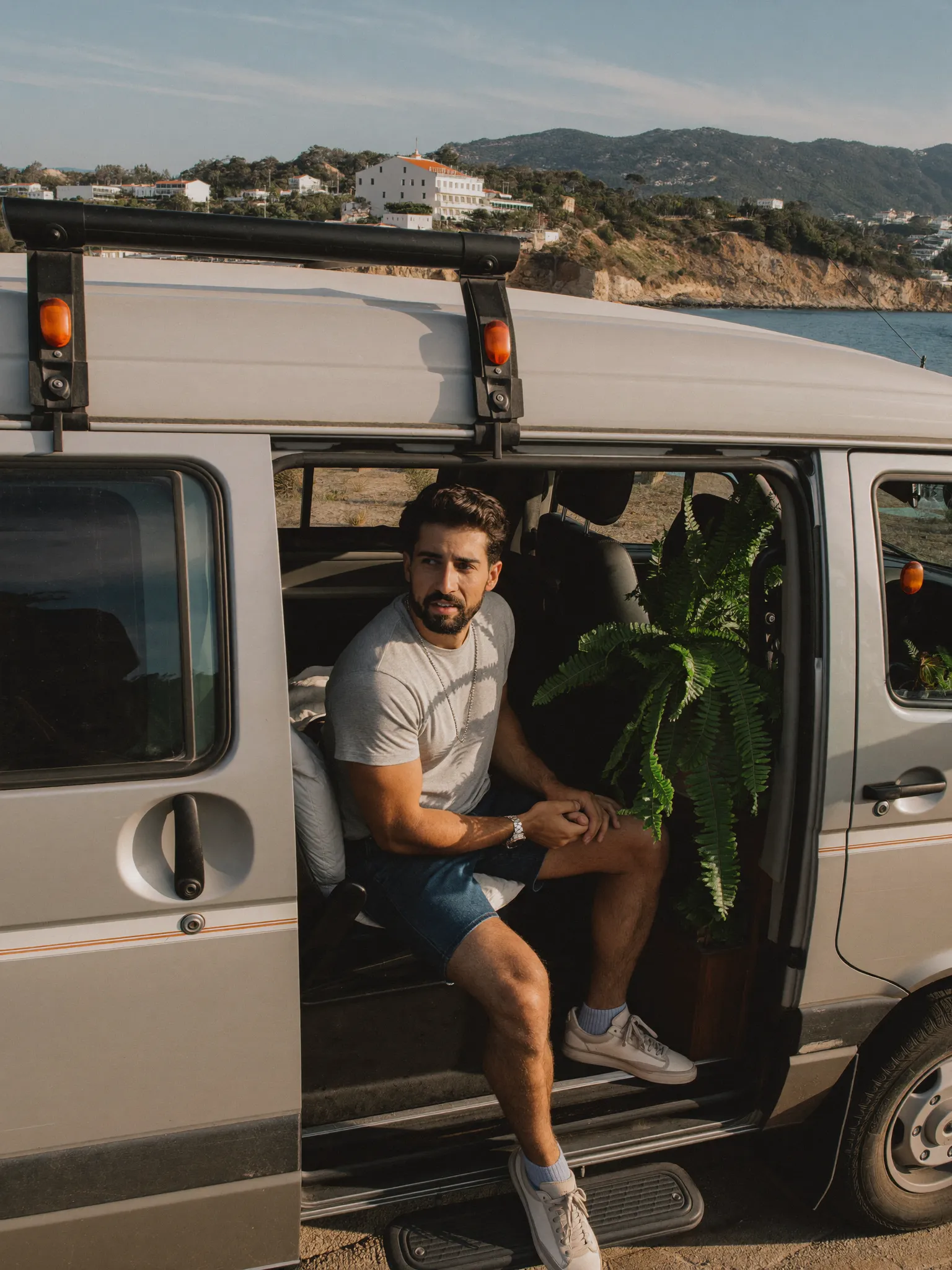 Ben inside his camper van with a leafy fern by the window